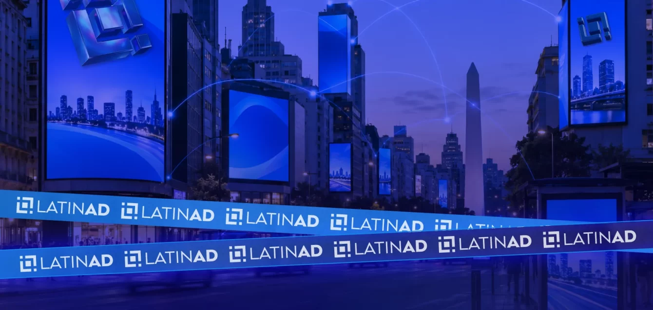 Edificios de una ciudad de noche con el logo de LatinAd en una pantalla